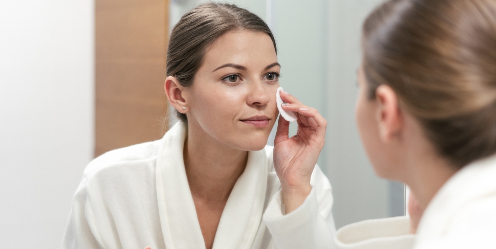 woman using cotton pad to remove makeup